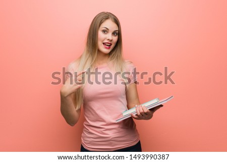 Young pretty russian girl surprised, feels successful and prosperous. She is holding books.