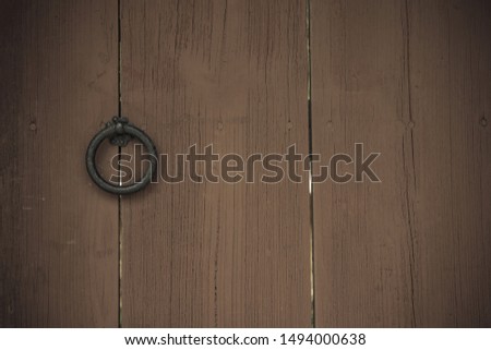 Old gates, wide planks, natural texture. Iron handle in the form of a ring. Locked door. Vintage style, vignetting.