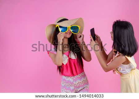 Two Asian girls who are friends are happy and have a pink background.