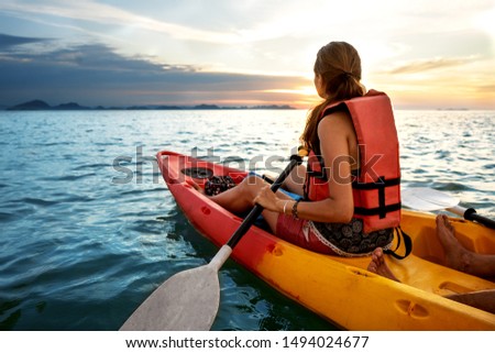 Couple kayaking together. Beautiful young couple kayaking on lake together and smiling at sunset Royalty-Free Stock Photo #1494024677