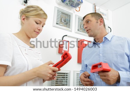 man and woman checking the fire alarm system