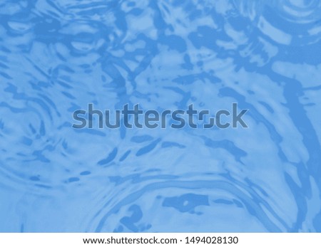 Concentric waves on blue water surface after falling drops, top view
