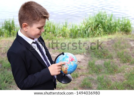 schoolboy in a black suit walks in nature