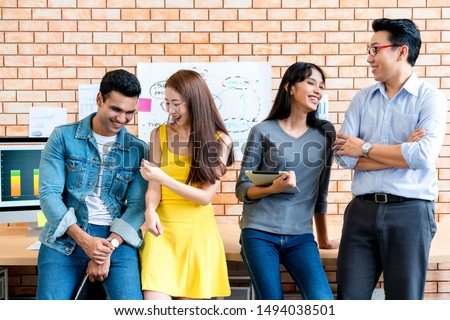 Group portrait of confident male and female creative designers standing together in modern design office background