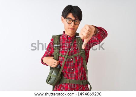 Chinese hiker man wearing backpack canteen glasses over isolated white background looking unhappy and angry showing rejection and negative with thumbs down gesture. Bad expression.