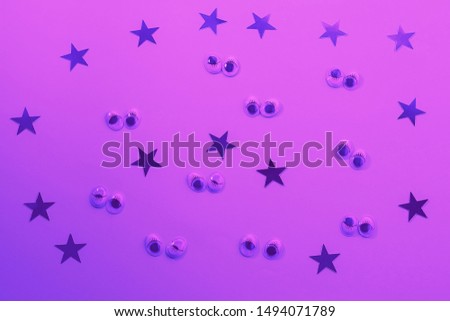 Decorative eyes on a lilac background in neon light. Halloween trick or treat concept. Creative concept for halloween. Flat lay, top view, copy space