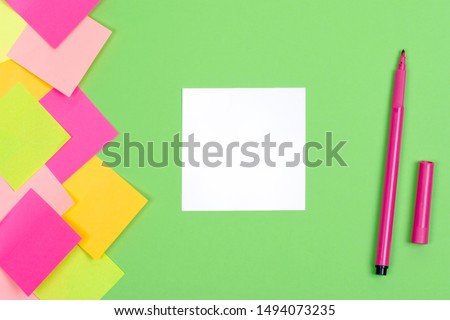 A writing sheet and a felt-tip pen. Green background. Bright stickers on the side. White sheet of paper