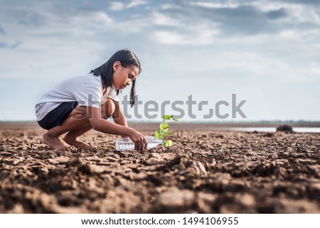 Asian girl watering green plant in dry land,Crack dried soil in drought and ,Climate change from global warming. Royalty-Free Stock Photo #1494106955