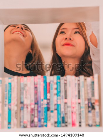 two Girls student search a book at the library 
