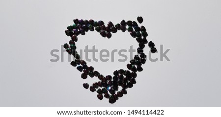 Silhouette of a heart in a scattering of small decorative colored pearl hearts (empty inside, abstraction)