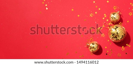 Creative Christmas concept. Shiny gold disco balls over red background. Flat lay, top view. New year baubles, star sparkles. Party time. Greeting card.