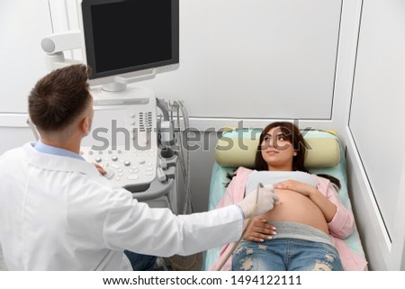 Young pregnant woman undergoing ultrasound scan in modern clinic