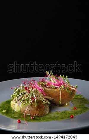 Grilled avocado with spicy sauce based on chili pepper and garlic. The concept of the restaurant menu and the beautiful presentation of the dish. Photo on a black background.