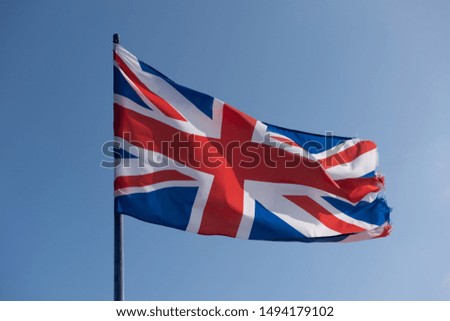 
Union Flag of the United Kingdom flying from a flag pole on a clear blue sky background. The flag is frayed at the edge which could be a metaphor for the current state of the UK.