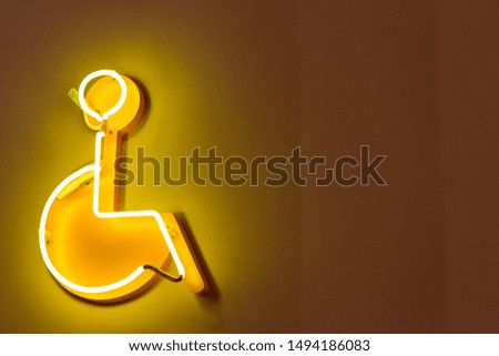 a sign depicting a disabled person on a wheelchair made of neon lamps