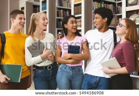 Team of international students having fun in campus library, laughing together
