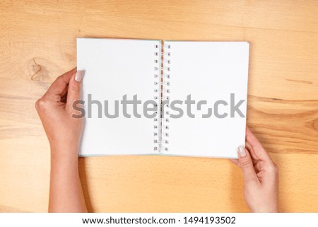 Woman hand holding blank paper on wooden background.