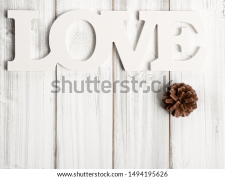 White love  text and pine cone decoration on wooden background
