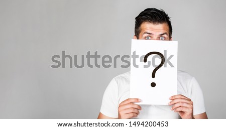 Portrait of man, peeking behind of interrogation symbol. Question mark, symbol. Pensive male. Man a question. Doubtful man holding Question Mark. Problems and solutions. Copy space. Royalty-Free Stock Photo #1494200453