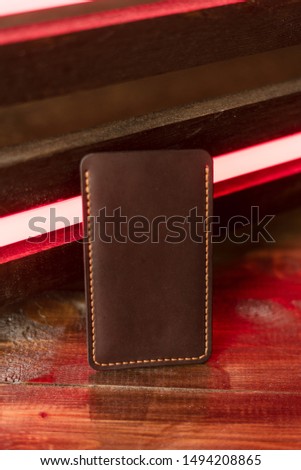Leather phone case on a wooden background in neon light.