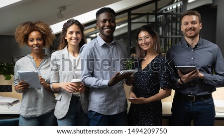 Smiling multiracial business team with african male leader standing together looking at camera in office, happy international diverse employees professionals company staff group corporate portrait Royalty-Free Stock Photo #1494209750