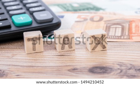 Tax word writen on wooden cubes. Euro banknotes Laid out in a semicicircle and calculator. Money finance earning sector concept. Copy space for text. Taxes and spending concept.