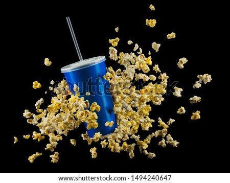 Blue cup with cap and flying popcorn isolated on black background. Concept of refreshments in cinema or watching movies