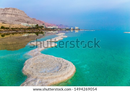 Azure sea water is full of healing salts. Small islets and path of salt in the water. Early morning at the resorts of the Dead Sea. Israel. Concept of ecological, medical and photo tourism