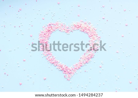 Valentine's Day. Heart made of pink confetti on blue background. 