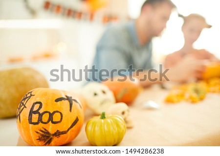 Close-up of pumpkins decorating for Halloween with family of two sitting at the table at home