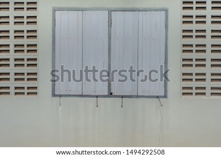 Wooden windows surrounded by brick vents, the white brick blowhole on old white wall.