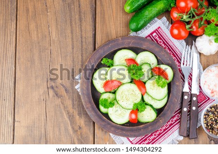 Diet salad of fresh cucumbers and tomatoes, cut into slices on wooden table. Studio Photo