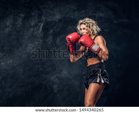 Blonde experienced boxer is demonstrating her tactic attack wearing special gloves.