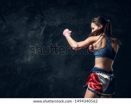 Beautiful sportive woman is warming up before training while posing for photographer.