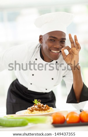 happy afro American chef in white uniform making delicious hand sign