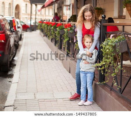 young woman with pretty girl standing on the street