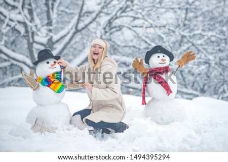 Funny snowmen. Happy smiling girl make snowman on sunny winter day. People in snow. Snowman. Beauty Winter Girl with snowman in frosty winter Park