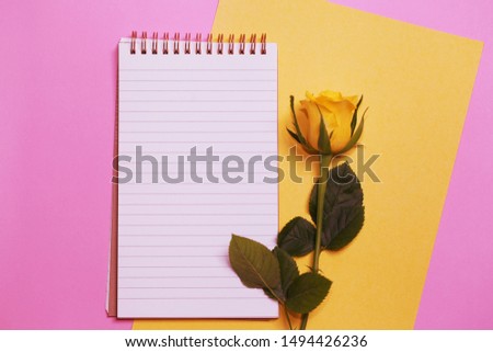 Opened notepad with a Yellow Rose on the pink background.