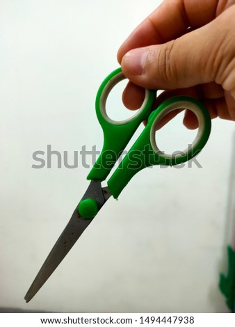 Green scissors in the hand