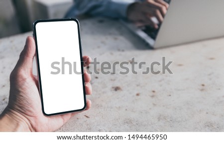 Mockup image blank white screen cell phone.men hand holding texting using mobile on desk at home office. background empty space for advertise text. contact business,people communication,technology 