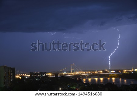 thunderstorm in the city at night against the background of the bridge.