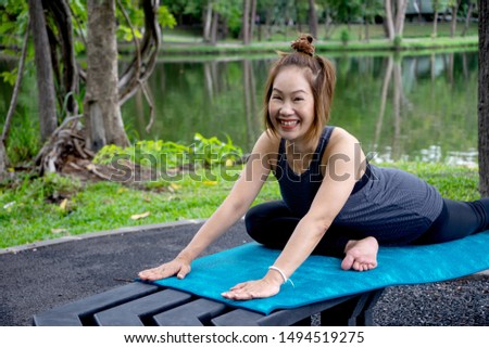 Woman more than 50 year old practicing yoga outdoor location near the lake in the park area. enjoy nice day in nature and positive energy. Happy and smile 