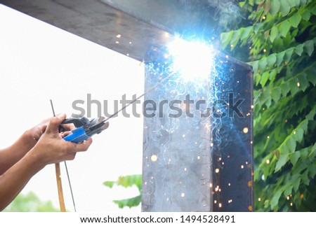 A close-up shot of an angle grinder on the background of a blacksmith who repaired the welding machine using professional equipment in the workshop. Blacksmith in white glove, blacksmith, soldering me