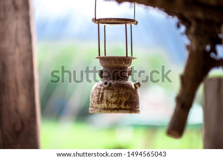 The blurry background of a metal lantern or antique decorative hanging display shows tourists taking pictures as souvenirs while traveling.