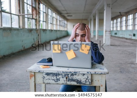 Photo of a student in blue shirt with a laptop in front of him, preparing for the exam. Difficulty in learning, education concept