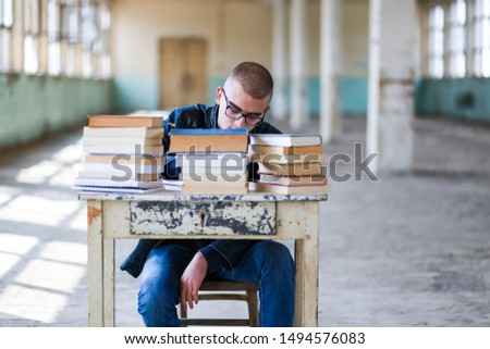 Photo of a student with a stack of books in front of him, preparing for the exam. Retro concept, old building
