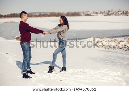 Cute couple have fun. Boy and girl in a winter park. Man in a red sweater. Brunette in a gray sweater. Loving couple walking around the ice