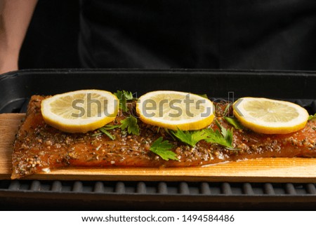 Chef cooking, seafood, red fish grills with smoke, salmon or trout on a black background. Movement, Restaurant menu, recipe book, Asian cuisine, homemade recipe. Horizontal photo, close up