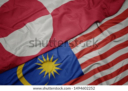 waving colorful flag of malaysia and national flag of greenland. macro