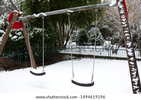 ​Playground safety during winter. Lonely swings at empty children's playground covered with snow. Winter solitude.